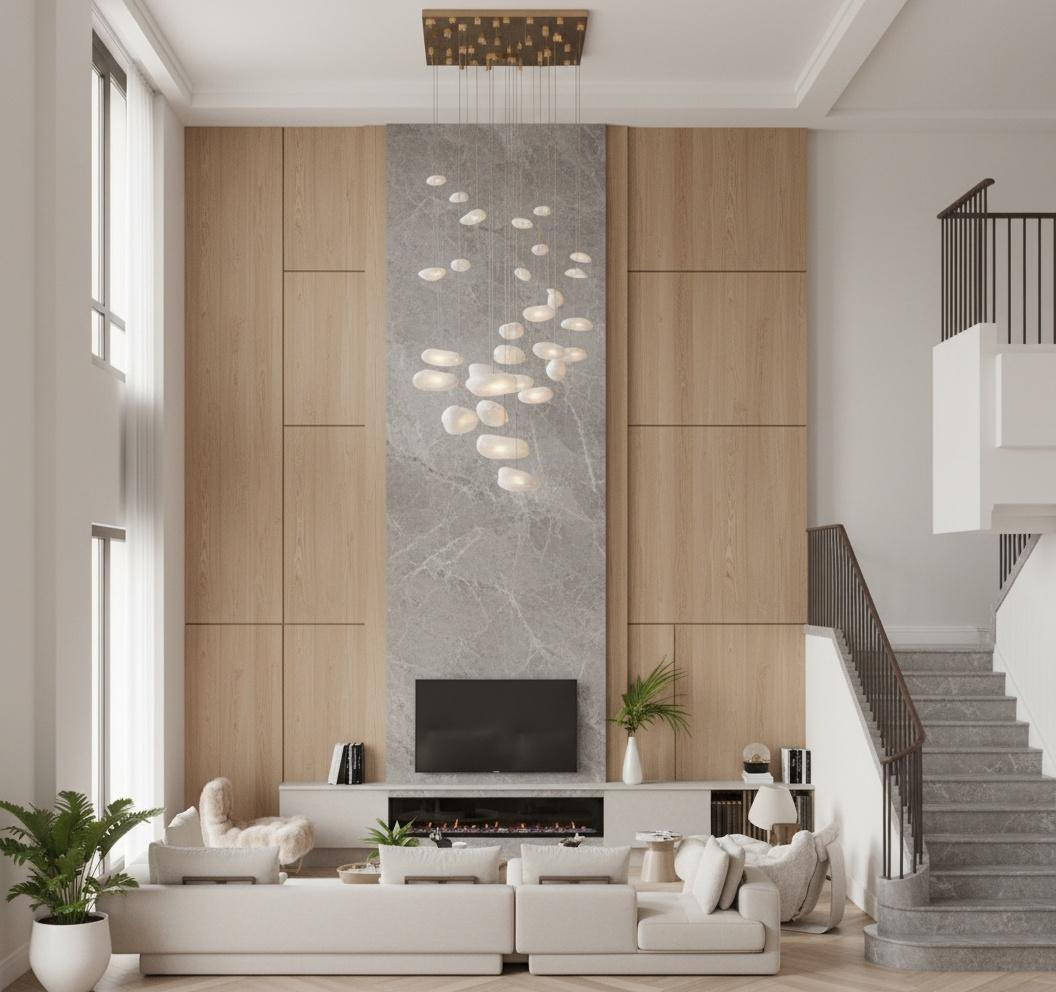 An incredibly lifelike, richly detailed, photorealistic interior photo of a living room set in a modern, airy apartment during midday in spring. The scene is illuminated by soft, diffused natural light pouring in through large windows, creating a bright and inviting atmosphere. Captured with a wide-angle lens, emphasizing the luxurious textures and spaciousness, the rendering showcases a statement fireplace with a dramatic marble surround and flanking wood-paneled walls. A cluster of organic, stone-like pendant lights descends from the ceiling, adding an artistic focal point. Plush, cream-colored sofas are arranged for comfortable conversation, complemented by a faux fur accent chair that hints at a touch of shabby chic warmth. The sophisticated design is further enhanced by the sleek grey marble staircase that ascends to an upper level, its dark metal railing providing a striking contrast, all contributing to a feeling of refined elegance with a relaxed, sophisticated vibe.