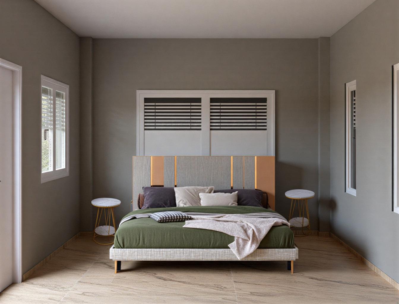 The photo presents a bedroom interior bathed in a soft, diffused light, suggesting an overcast day. The space is defined by its simplicity and a subtly rustic aesthetic. The focal point is a bed, with a muted green comforter casually draped, complemented by a variety of pillows in shades of gray and white. The headboard has a light, undefined texture that adds a touch of rustic charm. Flanking the bed are two small, round side tables featuring white marble tops and slender gold-toned metal frames. The walls are painted in a uniform gray, offering a blank canvas that allows the textures and colors of the furnishings to stand out. The floor is covered in large, light-colored tiles, adding a touch of modern sophistication to the room. Light streams in through a window with blinds, casting subtle shadows and highlighting the room's clean lines and minimalist design. The undefined style of the room gives it a sense of modern tranquility.