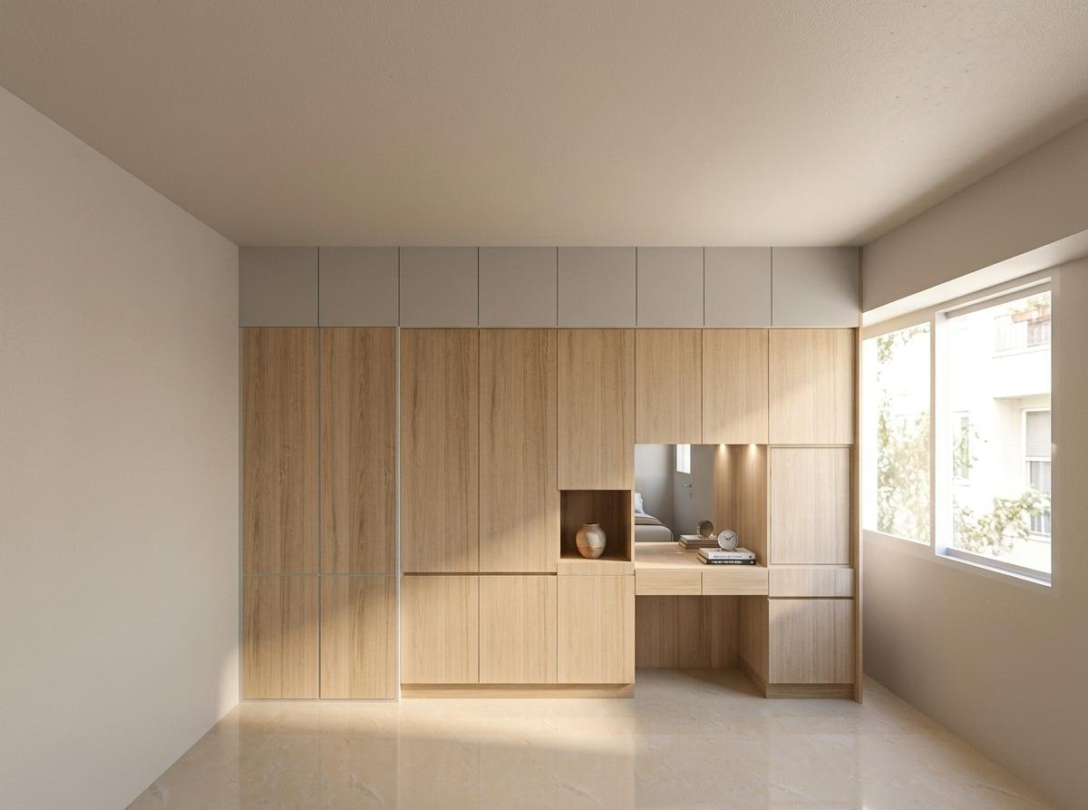 A professionally shot photograph of a minimalist modern bedroom featuring a large built-in light oak wardrobe and integrated vanity desk, showcasing a beautifully warm and inviting atmosphere. Soft, diffused ambient light glows gently across the ceiling, while bright, natural afternoon daylight streams through the large window on the right, casting soft, elongated shadows and creating a natural gradient on the matte plaster walls. The light oak wood panels on the wardrobe and desk exhibit realistic, tactile grain patterns with a subtle satin sheen that catches the light beautifully. The polished light beige floor has a natural, high-fidelity sheen, softly reflecting the window light and the structure of the wooden cabinets with realistic, slightly imperfect clarity. The vanity niche features small built-in warm downlights that cast a cozy, targeted glow onto the desk surface, with the inset mirror cleanly reflecting the opposite wall. The entire scene is captured with a wide-angle lens, exhibiting tack-sharp focus, natural color saturation, a warm color temperature, and a gentle touch of organic photographic grain that eliminates any digital rendering feel.