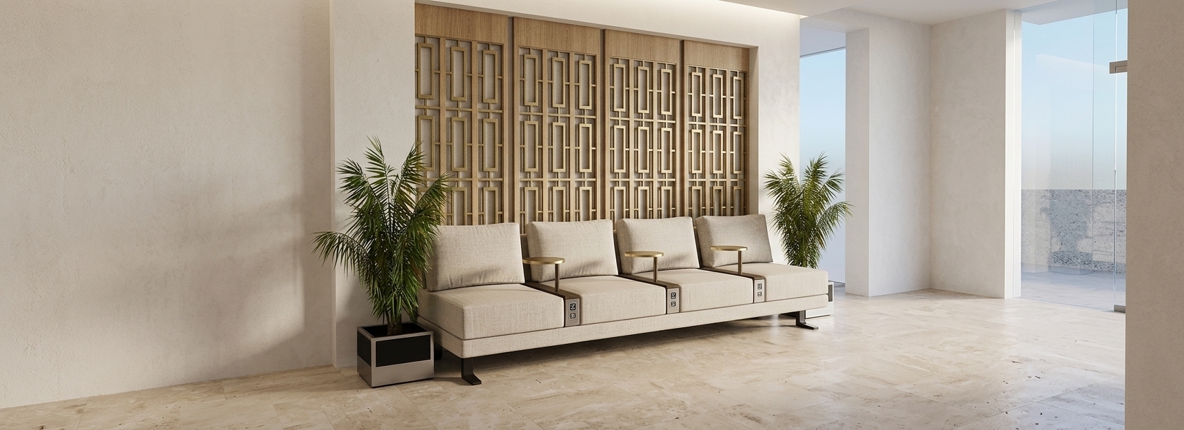 The photo presents an inviting and meticulously designed office waiting area, subtly infused with a sophisticated French country charm through its curated palette and architectural details. A long, contemporary four-seater bench anchors the space, upholstered in a soft, light beige fabric, possibly a textured linen, which immediately conveys warmth and comfort. Each individual seat is thoughtfully appointed with an integrated, sleek black circular side table, suspended from a dark metal armrest, offering convenience for guests. The focal point of the design is the striking back wall, featuring an elegant architectural screen. The upper section showcases light wooden panels, lending natural texture, while the lower part consists of a series of repeating geometric patterns set within dark frames, filled with lighter, possibly frosted inserts. This intricate, almost lattice-like detailing, while precise and modern, beautifully echoes the decorative craftsmanship and attention to detail often found in French country aesthetics, providing a refined, charming backdrop. Tall, vibrant green palm-like plants in sleek black planters with silver accents frame the seating on both ends, introducing a refreshing organic element to the otherwise structured environment. The floor is covered in large format grey tiles, complementing the serene beige walls that flank the waiting area and recede into broader hallways, suggesting an expansive yet orderly office setting. Soft, ambient lighting bathes the scene, enhancing the calm and welcoming atmosphere, making it a peaceful and functional space within a professional context.