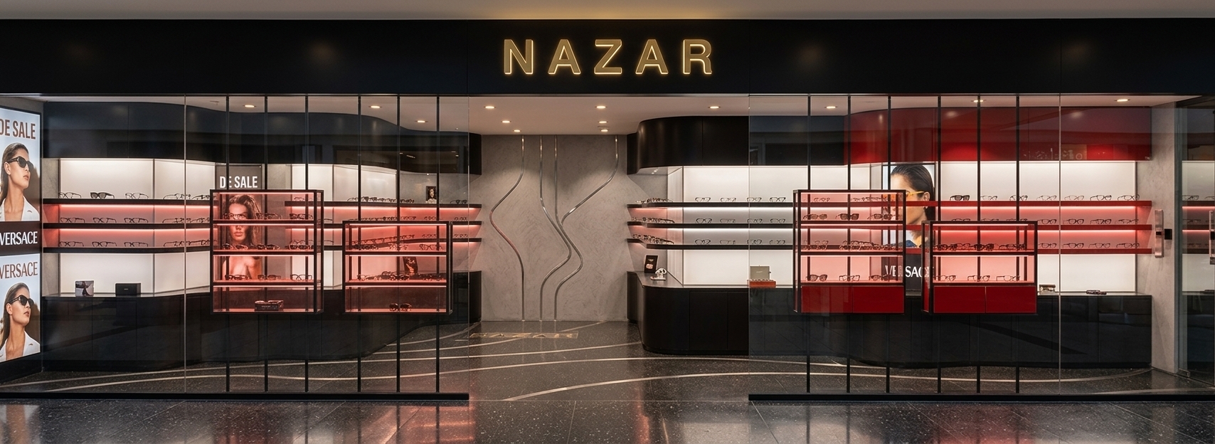 A professional architectural photograph of a high-end modern eyeglass boutique storefront. The storefront is captured from a straight-on, eye-level perspective, preserving the exact geometry and composition of the space. The upper facade features a matte black metal fascia with the word NAZAR rendered in clean, backlit yellow-gold letters that emit a soft, warm glow. Through the large, seamless glass windows, which exhibit realistic, faint reflections of the exterior surroundings, the warm and inviting interior is fully visible, illuminated by recessed spotlights. The display cases feature a combination of polished premium metal frames, red-tinted translucent glass panels, and clear glass shelves showcasing subtle optical details. The curving interior walls are finished in a finely textured, matte light grey plaster, integrated with organic metallic wave patterns. The floor is a dark polished terrazzo with a subtle satin finish, catching gentle reflections from the display lights. The shot is exceptionally sharp, clean, and realistic, with natural light falloff, soft atmospheric depth, and micro-textures on the metallic and glass surfaces that define a true-to-life retail environment.