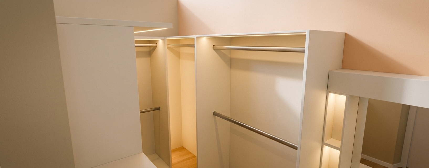 An architectural interior photograph of a modern minimalist walk-in closet, maintaining the precise geometry, layout, camera angle, and structural design of the source image. The custom built-in cabinetry features smooth, low-sheen matte off-white lacquered panels with delicate micro-textures and subtle, realistic edge bevels. Integrated warm 2700K LED accent lighting concealed along shelf undersides casts a soft, inviting glow into the deep cabinet bays and open hanging sections, creating rich contact shadows and realistic global illumination depth. The clothing hanging rods display a refined brushed stainless steel finish with subtle metallic reflections and fine surface grain. The floor visible in the lower nook is warm light oak hardwood with a faint satin finish reflecting ambient glow. The background walls are painted in smooth matte beige and soft peach tones, illuminated by gentle indirect daylight blending seamlessly with the warm ambient LEDs. Captured with a professional wide-angle lens in sharp architectural focus, featuring balanced exposure, subtle natural film grain, faint lens vignetting, and photorealistic ray-traced lighting physics.