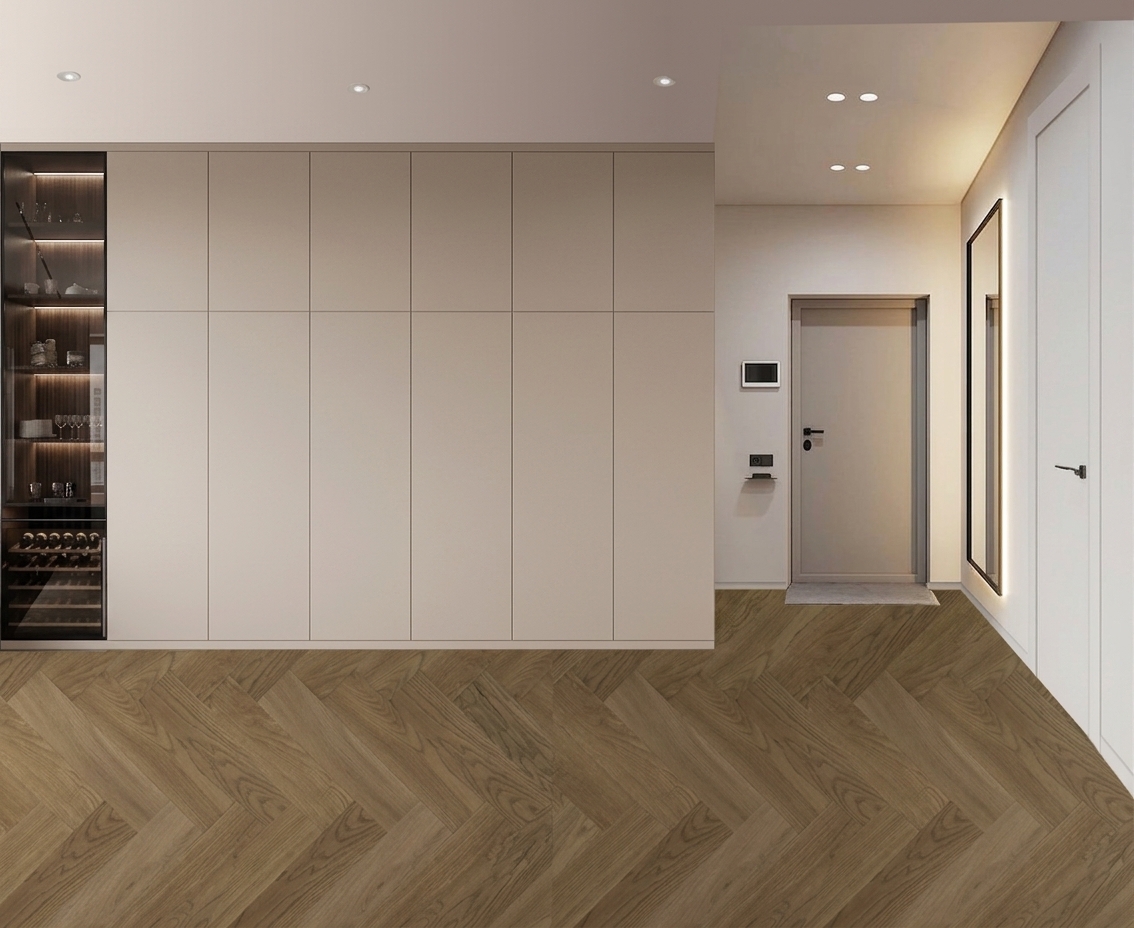 A wide-angle professional architectural photograph of the modern interior scene captured with clean optical accuracy, preserving the exact straight-on perspective, spatial layout, furniture proportions, and structural geometry of the input image. The natural oak herringbone parquet flooring displays realistic wood grain textures, subtle matte-satin sheen, and fine micro-beveled seams that catch soft ambient highlights. The floor-to-ceiling storage wall is composed of ultra-matte beige-taupe lacquered panels with tight, precise door seams, completely free of artificial CGI gloss or exaggerated reflections. On the far left, the illuminated display unit behind clean, faintly reflective glass reveals dark timber shelving and organized glassware lit by warm integrated LED strips. Soft, neutral daylight evenly fills the hallway and living space, complemented by recessed warm downlights and a subtle backlit glow behind the tall accent mirror. Surrounding painted plaster walls feature fine surface micro-textures, while the neutral grey entry door, matte black hardware, video intercom unit, and interior doors exhibit authentic contact shadows, soft ambient occlusion, and physical material depth, producing a believable, professionally shot interior photograph without filters or digital embellishments.
