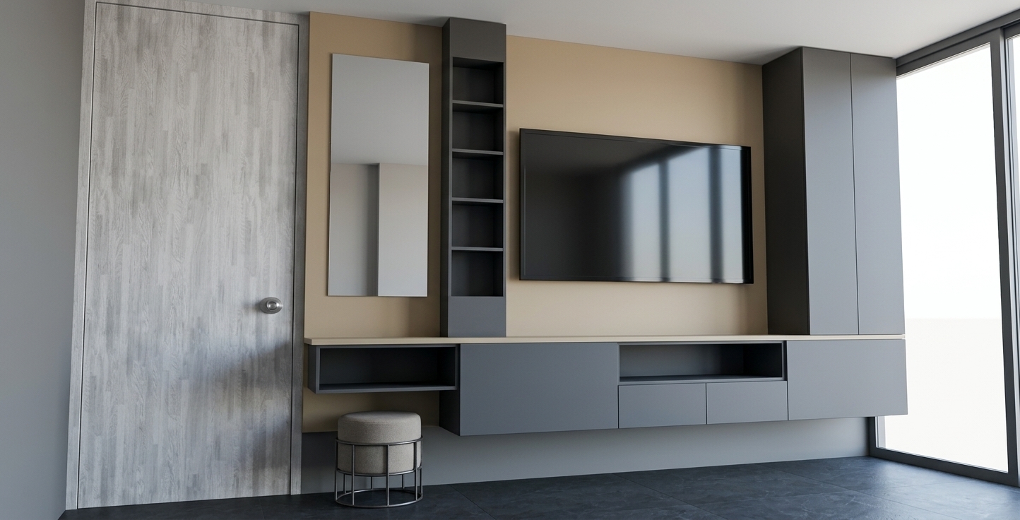 A professional interior architecture photograph capturing the exact geometric layout of the custom media wall unit, highlighting sleek finishes in warm sand beige and dark lead-grey. The scene is photographed with a wide-angle 24mm architectural lens at a straight-on perspective, faithfully maintaining every line, proportion, and object placement. Diffuse daylight streams in from the glass frame on the right, casting soft, natural drop shadows underneath the floating lead-grey drawers and inside the open sand-colored shelving alcoves. The sand-finished wall panels feature a refined matte tactile texture, while the lead-grey cabinet fronts display a subtle satin sheen that faintly catches ambient reflections. To the left, the light-toned door showcases a realistic whitewashed wood grain pattern, while the circular vanity stool features a finely woven grey upholstery texture sitting on a matte black steel frame. The mounted television screen and tall mirror present realistic glassy reflections with microscopic dust specs and subtle smudges visible under close inspection. The scene rests on smooth dark slate floor tiles under natural white balance, complemented by faint photographic grain, gentle edge vignetting, and precise material physics.