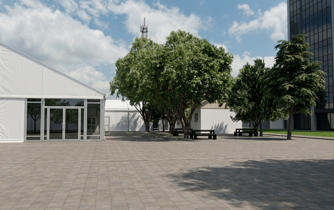 A realistic eye-level photograph of the outdoor courtyard under bright, diffused daylight with soft cloud cover. The large marquee tent on the left is fully enclosed with taut, white commercial vinyl tarpaulin stretched over the structural aluminum frame and clean glass entrance doors. Textured stone pavers cover the ground, catching realistic dappled shadows cast by the leafy green trees and dark wooden picnic benches, captured with crisp focus, natural color saturation, and subtle ambient reflections.