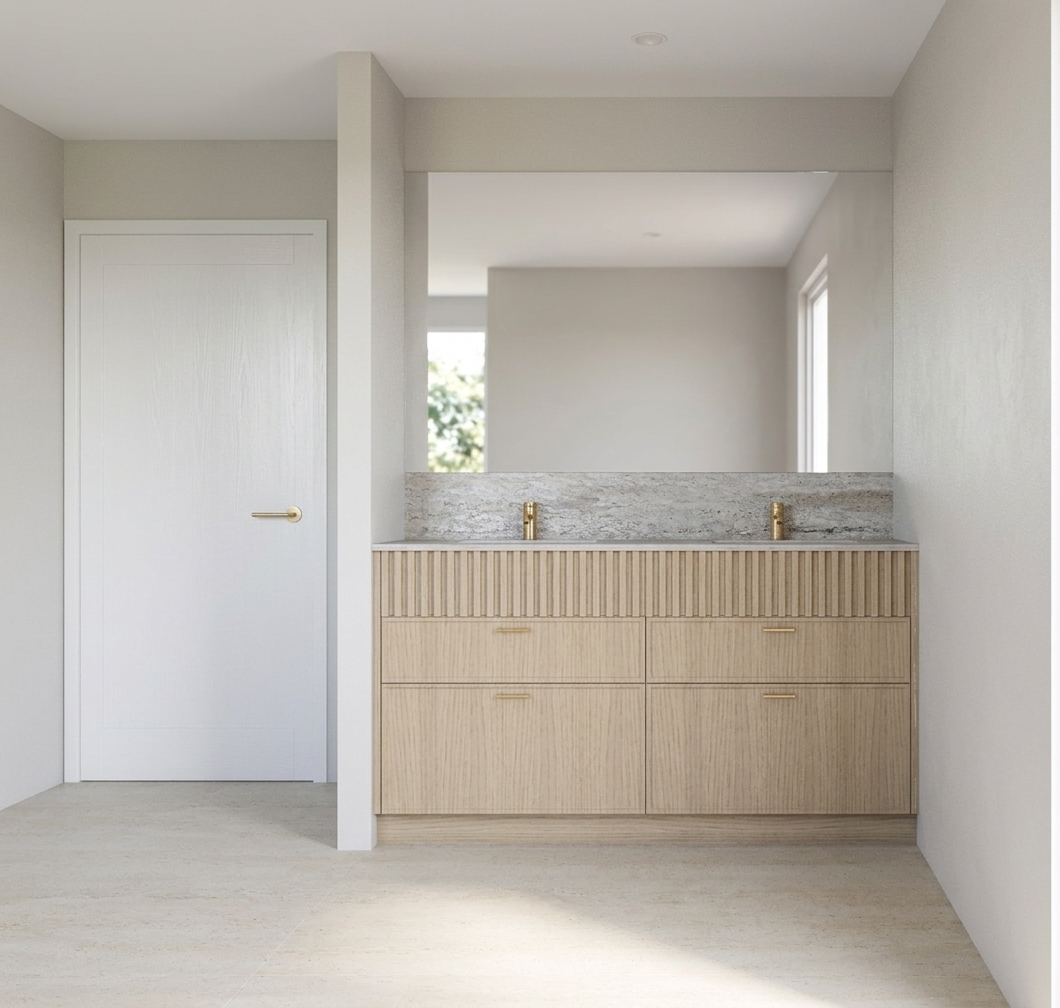 An architectural interior photograph of the modern bathroom vanity area illuminated by bright, natural midday daylight. The exact layout, geometry, and framing are faithfully preserved, highlighting the authentic tactile textures of the light oak fluted cabinetry, brushed brass handles, and textured stone countertop. Neutral midday sunlight fills the space with balanced ambient light and soft shadows, creating realistic specular glints on the gold faucets, gentle reflections across the large mirror, and realistic micro-textures on the matte painted walls and flooring, captured with crisp focus and natural dynamic range.