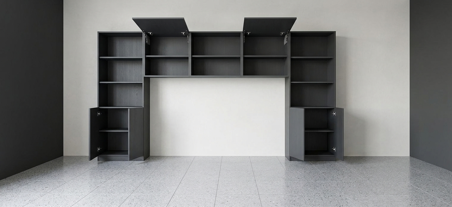An eye-level architectural interior photograph capturing the exact room layout and custom wall unit finished in a clean, matte anthracite grey texture, leaving the space devoid of any additional furniture. Soft, diffused daylight from the side illuminates the scene, casting subtle contact shadows across the pale background wall and light-toned tiled floor while removing all diagrammatic lines. The open cabinet doors and lifted flaps display fine joinery and satin metal hinge hardware, shot with a sharp mid-range lens, realistic material physics, neutral color temperature, and faint natural sensor grain.
