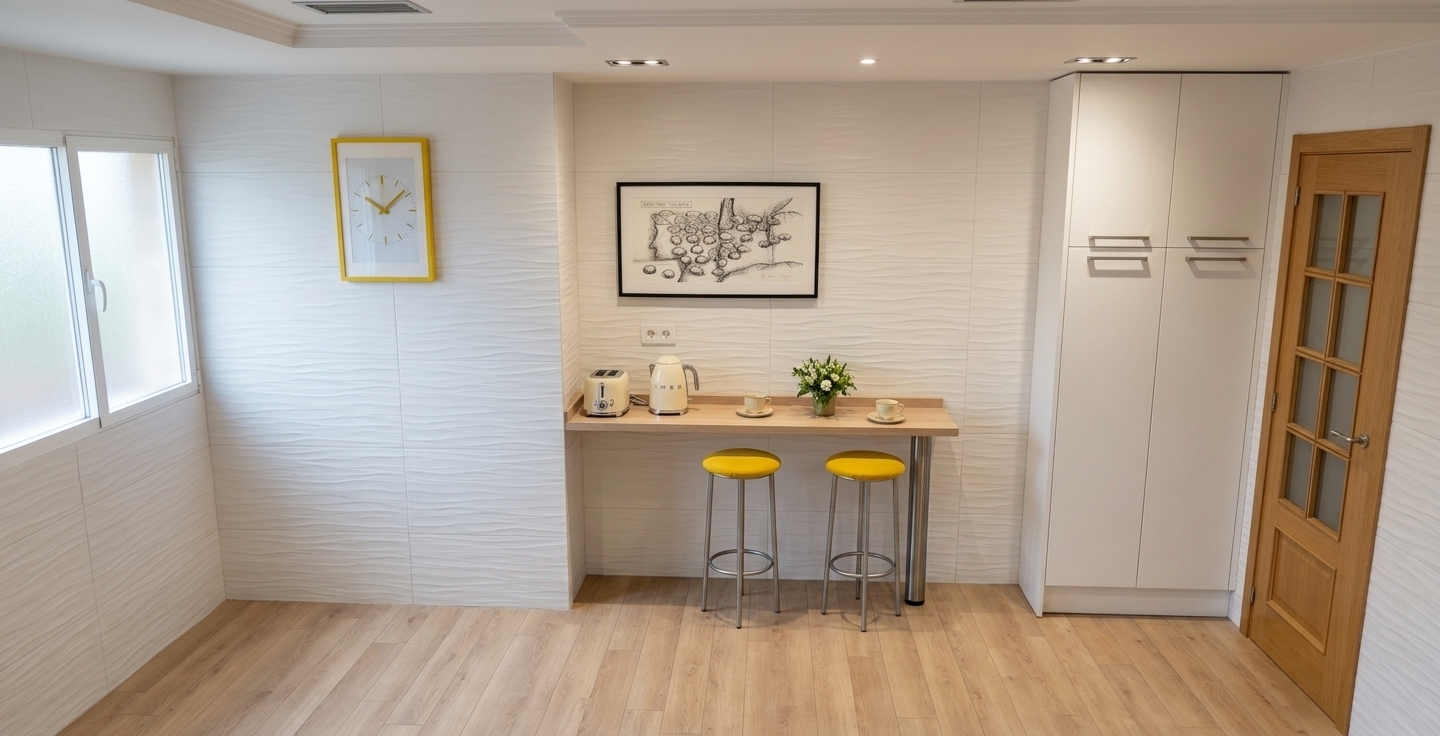 An incredibly lifelike, richly detailed, photorealistic wide-angle interior photo of a contemporary kitchen breakfast nook set in a modern apartment. The scene is illuminated by soft, natural light filtering gently through a frosted side window combined with recessed ceiling downlights, creating an airy, peaceful, and elegant atmosphere. Captured with a professional full-frame camera and a 24mm architectural lens, emphasizing the delicate undulating relief of textured white wall tiles and the matte grain of light oak plank flooring. A floating light-wood breakfast counter, anchored by a sleek brushed chrome support, features retro cream-toned appliances, fine ceramic cups, and a fresh floral arrangement, flanked by a pair of modern stools with vibrant yellow cushions. Perfectly balancing contemporary elegance, the composition is framed by seamless floor-to-ceiling white cabinetry, a warm glazed timber door, and a bright yellow-framed accent clock that harmonizes effortlessly with the vibrant details.