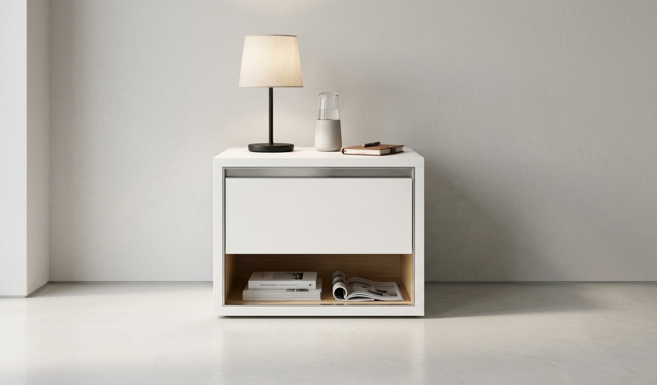 A crisp eye-level photograph preserving the exact framing and geometry of the nightstand, realistically textured in smooth matte white wood with subtle grain. Resting on the top surface is a modern bedside lamp casting a soft warm glow, alongside a sleek smartphone and a TV remote with delicate micro-reflections. Two hardcover books are stacked neatly inside the lower cubby. Soft ambient daylight mingles with warm 3000K accent light, creating natural contact shadows, captured on a sharp 50mm lens with authentic depth and fine material textures.