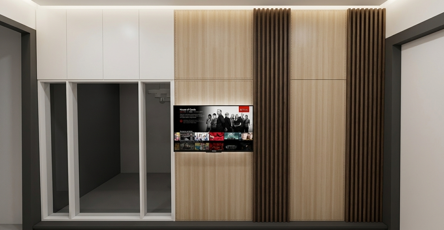 A sharp, eye-level architectural photograph reproducing the exact composition, geometry, and framing of the interior wall, illuminated entirely by soft, diffuse interior ambient lighting with zero sunlight or exterior window illumination. The TV backdrop and adjacent partition panel feature the realistic matte texture and fine linear grain of light wood HPL, contrasted by the rich, warm brown tones and defined vertical shadow grooves of the flanking fluted WPC composite slats. The wall-mounted television screen displays a vibrant interface casting a faint, authentic glow onto the panel behind it, while the white door frame and upper cabinets on the left exhibit clean semi-matte finishes, crisp joinery lines, and subtle ambient occlusion in the recesses. Captured with a straight-on perspective, the image features balanced indoor exposure, natural micro-surface textures, and fine camera sensor grain for genuine realism without changing any layout elements.
