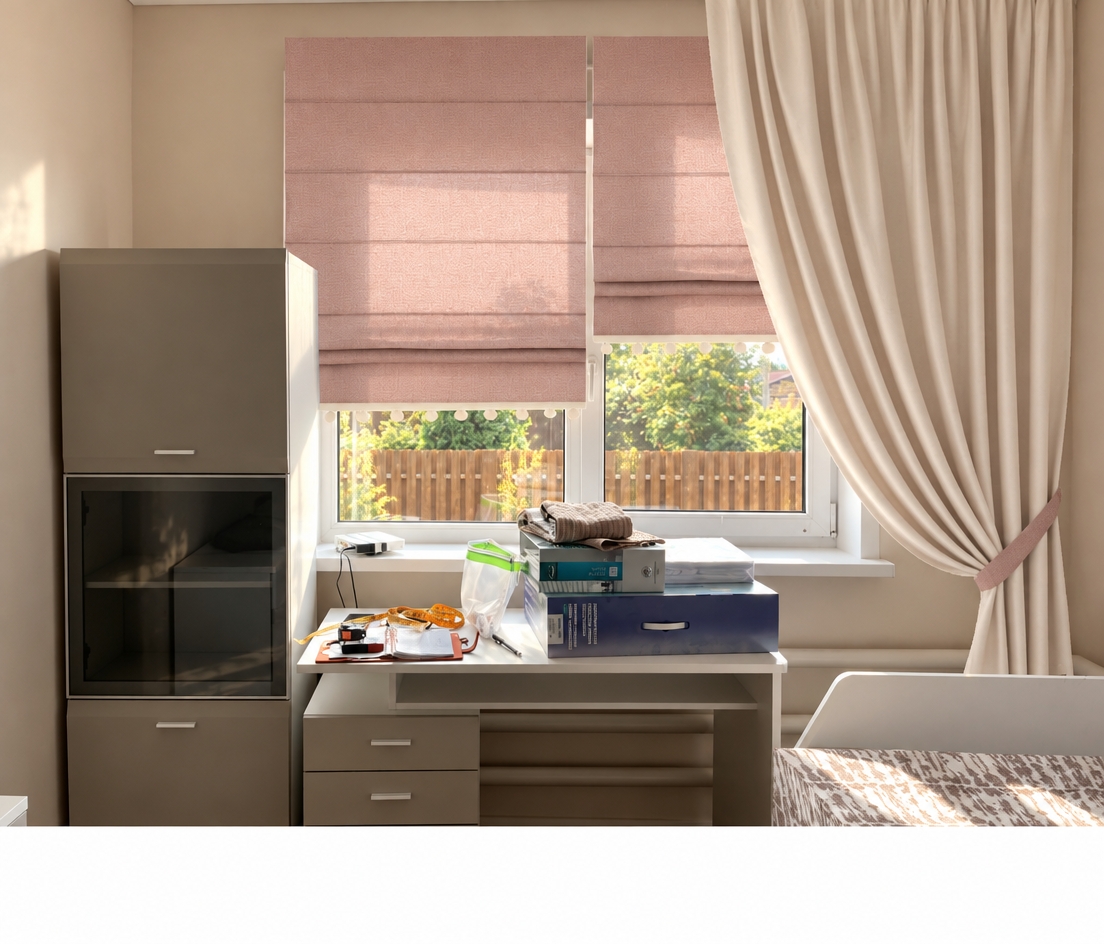 A photorealistic photograph of the room under bright summer midday light, preserving the exact composition, geometry, and placement of all furnishings. Clear, warm sunlight floods through the window, highlighting the fine woven texture and natural subsurface glow of the dusty-pink Roman shades, and casting soft contact shadows beneath the gathered folds of the cream curtain. The desk surfaces, clutter, and cabinet show authentic material physics, gentle specular highlights, and natural room bounce, while the outdoor greenery and wooden fence are realistically exposed with subtle atmospheric depth and faint film grain.