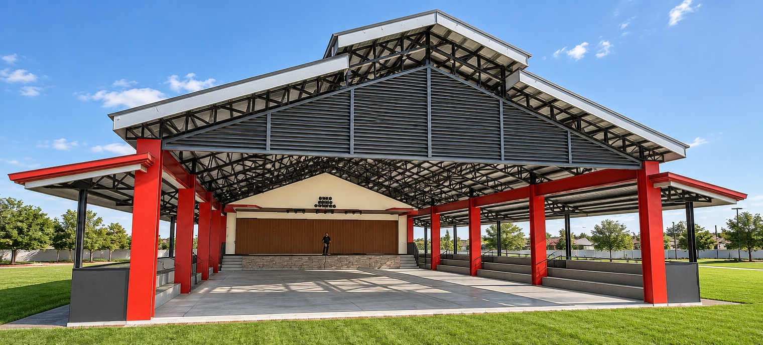 Architectural photograph captured with a wide-angle lens under bright midday spring sunlight, preserving the exact geometry and perspective of the open-air pavilion. Harsh overhead sunlight casts detailed geometric shadows through the dark steel roof trusses onto the smooth concrete floor. The vivid red structural columns feature realistic painted surface textures and subtle specular highlights. The covered stage, bleachers, and corrugated roofing are rendered with natural, authentic materials and ambient bounced light, framed against clean spring turf under a clear sky with sharp focus throughout.