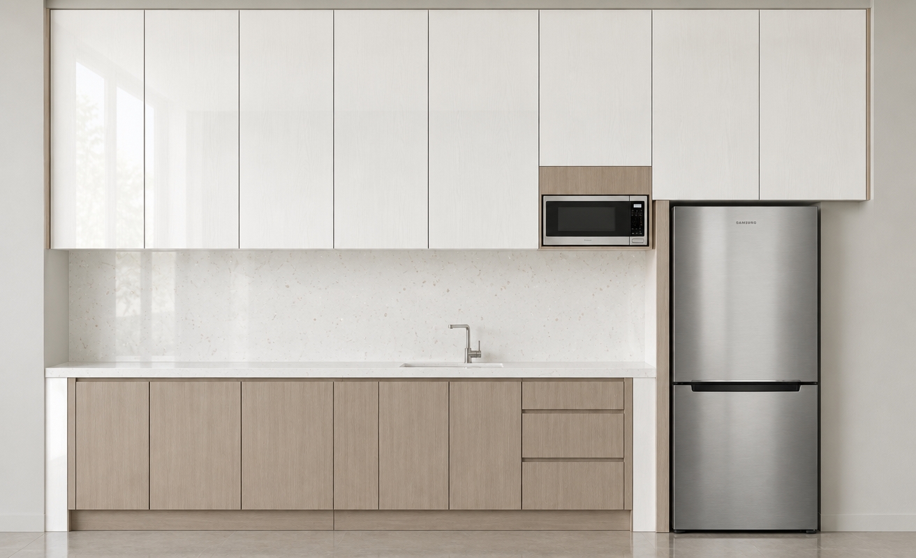 An incredibly lifelike, richly detailed, photorealistic interior elevation shot of a modern kitchen set in a minimalist haven. The scene is illuminated by soft, natural ambient daylight, creating a clean, serene, and sophisticated atmosphere. Captured with a 35mm prime lens, emphasizing the crisp contrast between the warm light greige woodgrain of the lower cabinetry and the luminous, glossy white woodgrain finish of the overhead storage. The seamless, white satin quartz stone countertop and matching full-height backsplash feature subtle, elegant crystal flecks that catch the light, providing a luxurious depth to the workspace. The composition is perfectly balanced, featuring a sleek stainless steel refrigerator standing flush against the cabinetry, while the integrated stainless steel microwave is tucked neatly into a matching wood-paneled niche. Every finish, from the smooth texture of the vertical-grain timber to the polished sheen of the stone, is rendered with precision, highlighting a minimalist aesthetic defined by clean lines and an uncluttered, high-end materiality.