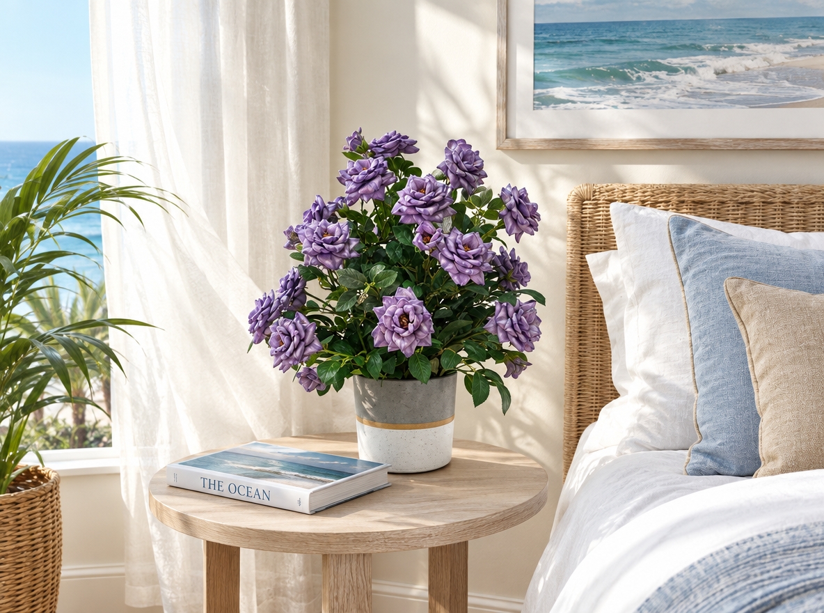 An incredibly lifelike, richly detailed, photorealistic medium shot of an airy coastal bedroom set in a sun-kissed seaside home. The scene is illuminated by radiant morning sunlight streaming through sheer, billowing curtains caught in a fresh coastal breeze, creating a tranquil, beachy, and effortlessly relaxing atmosphere. Captured with a 50mm f/1.8 lens, emphasizing the tactile textures of bleached oak, woven wicker, and soft botanical leaves. In this serene space, the refined potted rose arrangement rests beside an artfully placed ocean photography book on a sandy neutral wooden nightstand. Crisp white bed linens layered with soft cerulean and sandy-beige throw pillows face an expansive seascape wall art, while uncluttered surfaces, subtle nautical accents, and surrounding potted plants bring a casual, open, and harmonious warmth to this inviting coastal sanctuary.