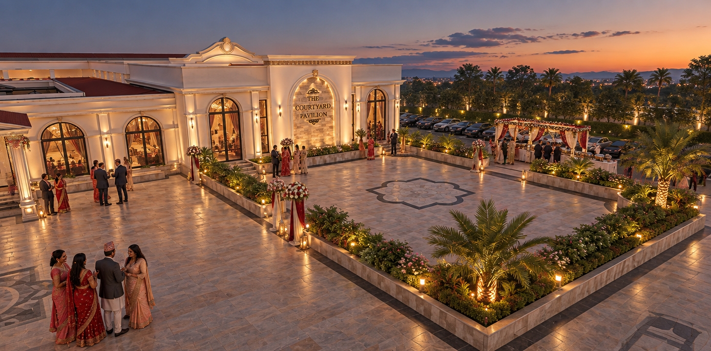 An architectural photograph of the neoclassical pavilion and courtyard during a warm late afternoon transitioning into a deep blue twilight sky. The building features realistic off-white plaster, crisp classical mouldings, and arched windows reflecting the golden horizon and soft interior lights. The ground is rendered in detailed square stone paving with polished dark granite borders, while the raised planters are populated with lush, photorealistic shrubs and palm fronds. An elegant outdoor Nepali wedding celebration animates the courtyard with naturally gathered guests in traditional attire and festive details, captured with balanced golden-hour directional illumination, realistic surface textures, subtle ambient occlusion, and faint lens vignetting.